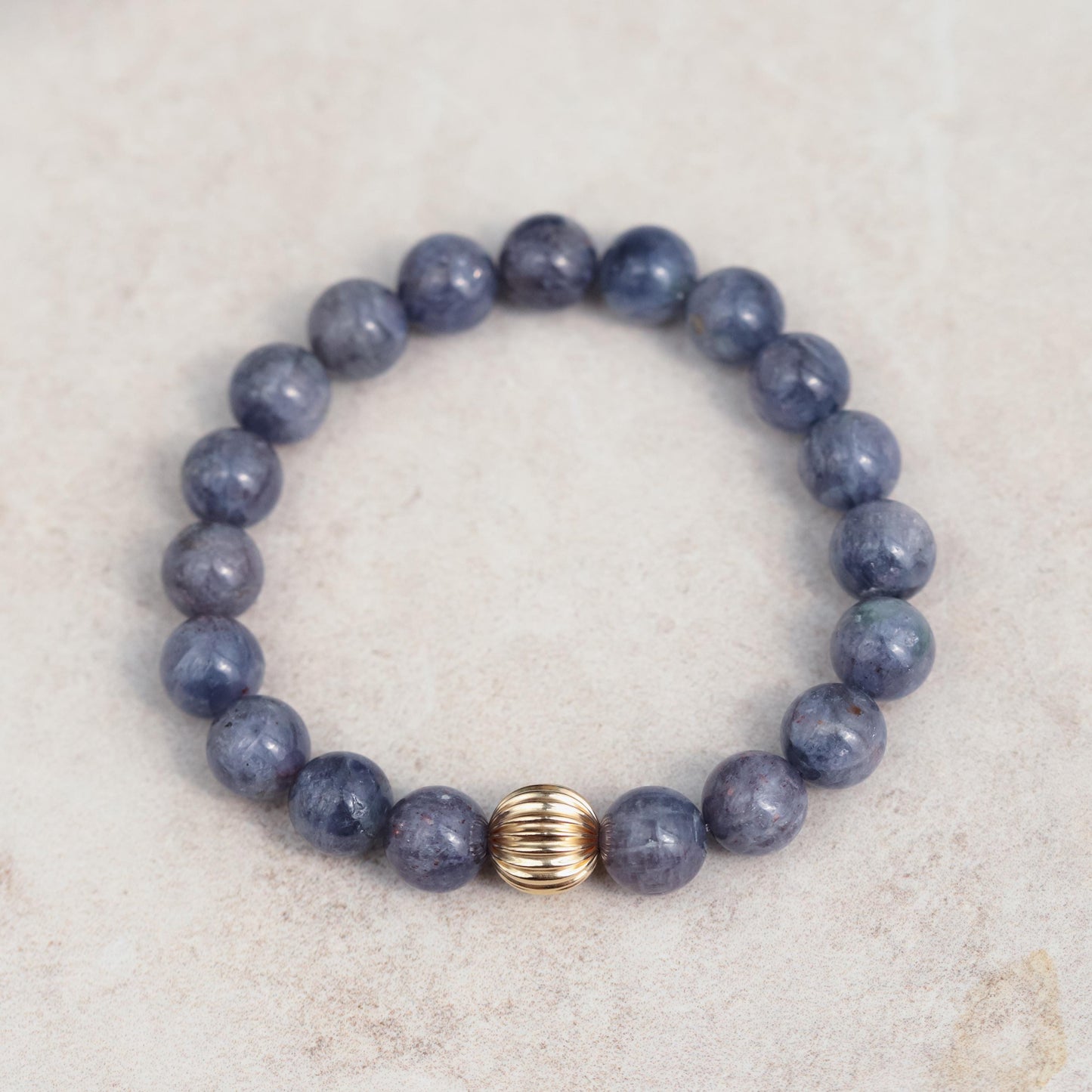 Iolite bracelet with 10mm beads from Earthly Abundance, showcasing polished blue-violet gemstones on a delicate elastic band.