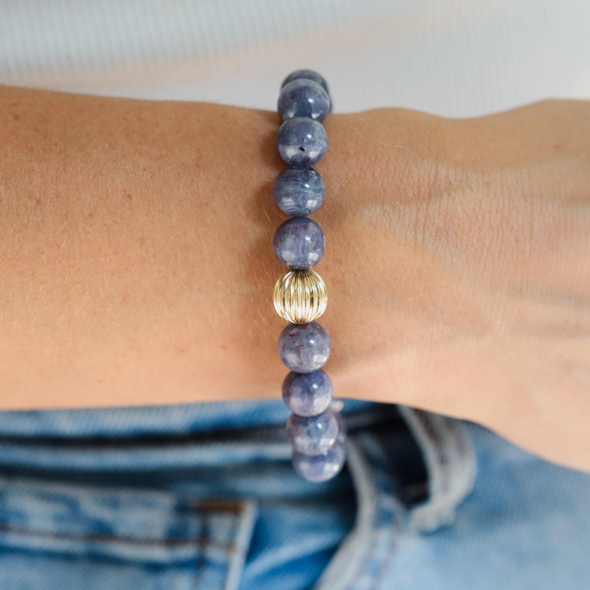 Iolite bracelet with 10mm beads from Earthly Abundance, showcasing polished violet-blue stones on a delicate elastic band.