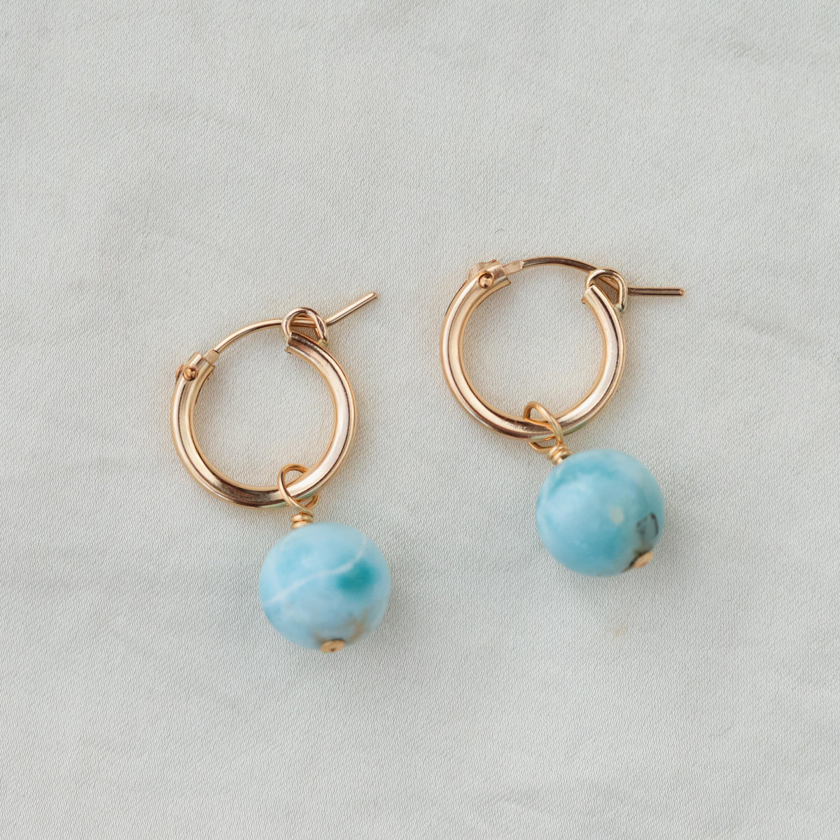 Dangle Larimar gemstone hoops earrings with 14K gold-filled setting, featuring vibrant blue stones and elegant design.