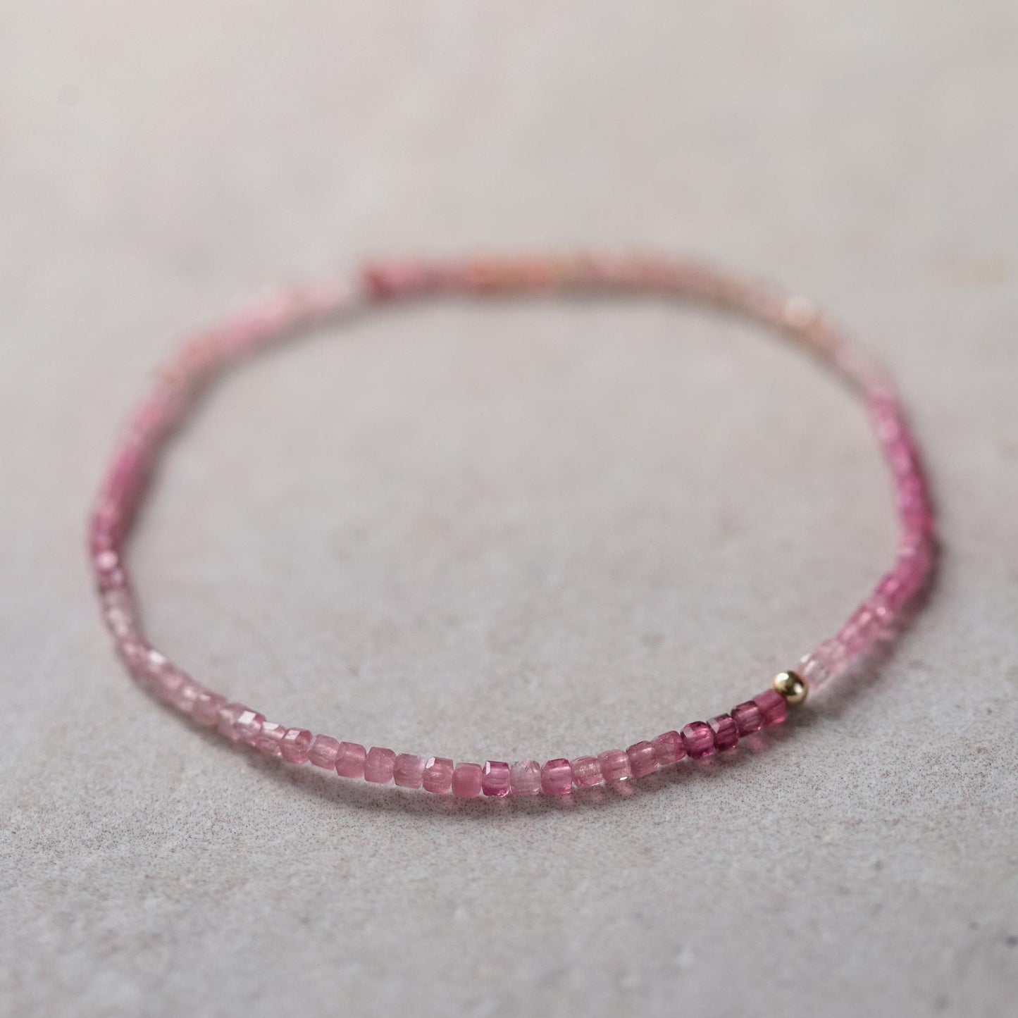 Pink tourmaline cube bracelet made with 14K gold, featuring vibrant pink gemstone beads on a delicate gold chain.