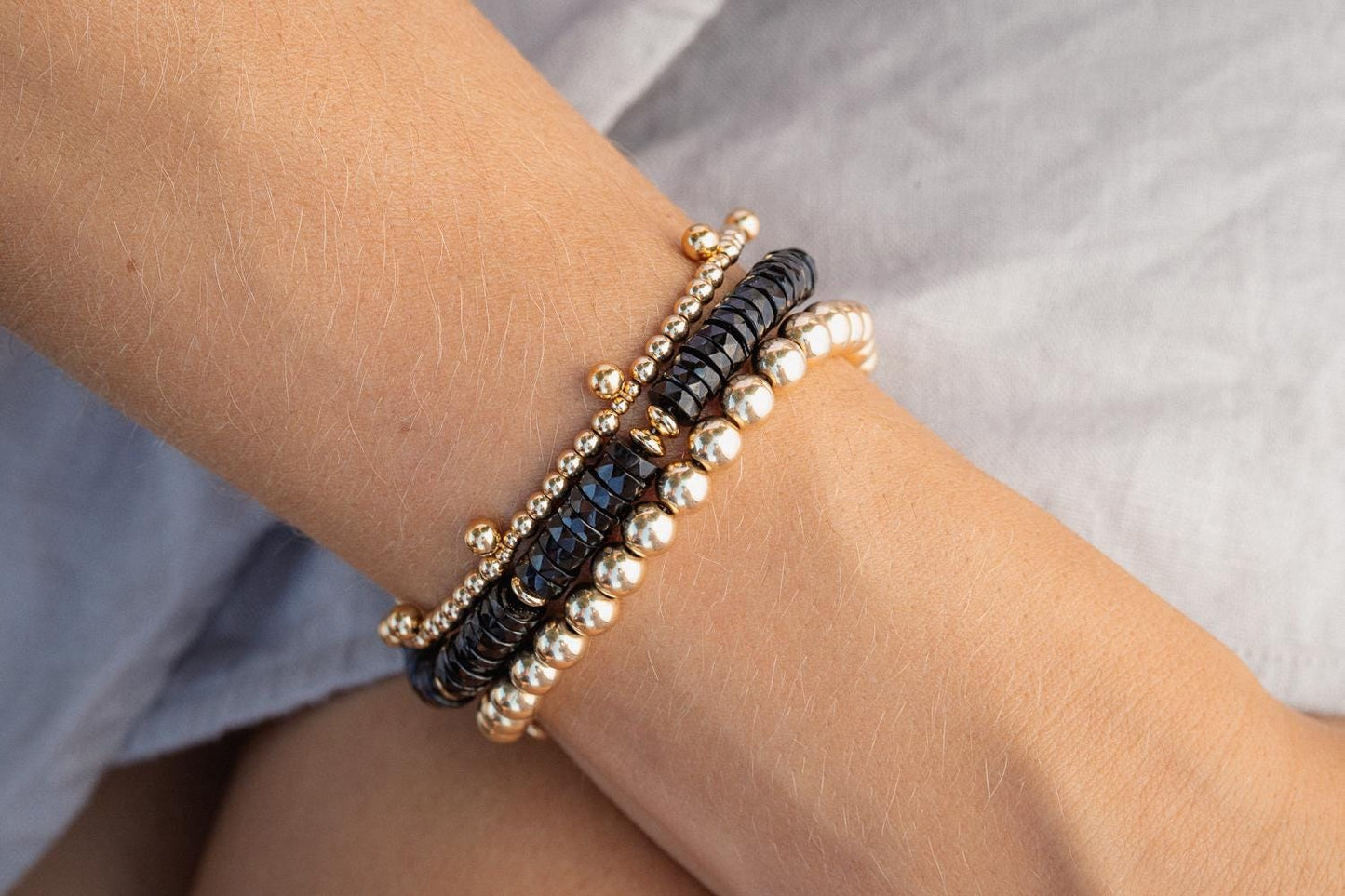 Black Tourmaline Heishi bracelet featuring small, polished black stones strung on an elastic band for a stylish, protective accessory.