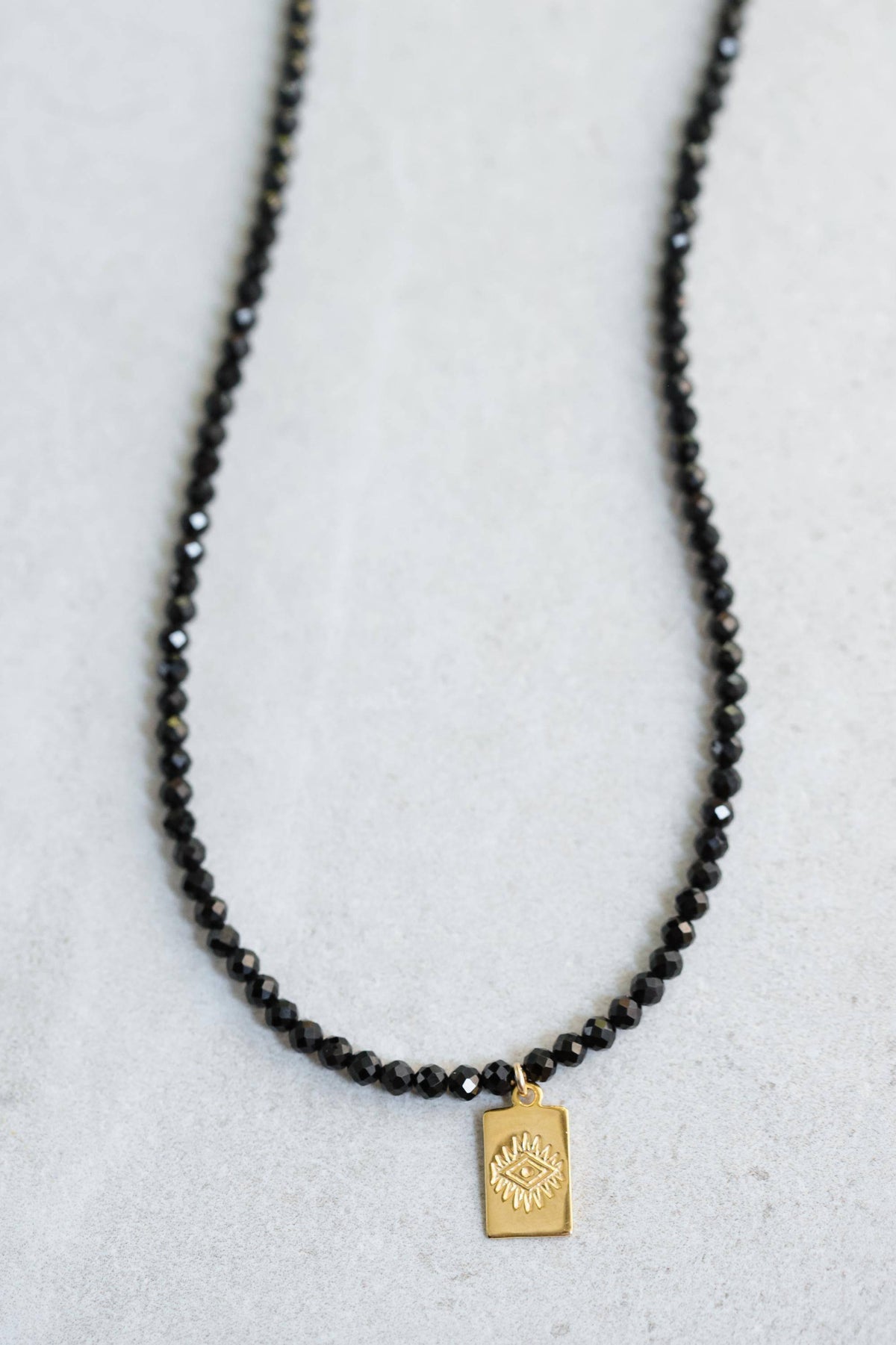 Black tourmaline evil eye necklace with protective pendant on a chain, by Earthly Abundance.