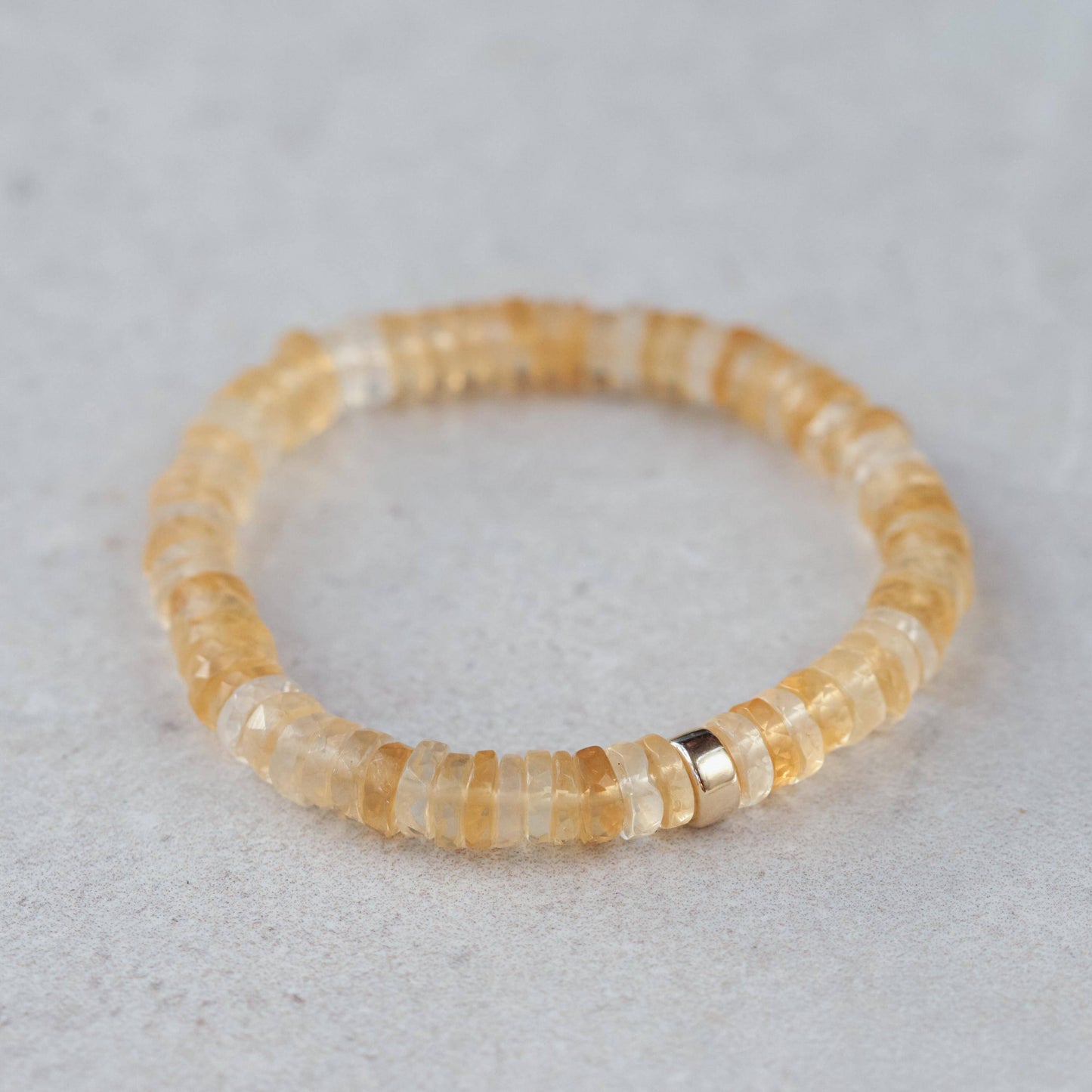 Citrine Heishi bracelet by Earthly Abundance with small orange gemstone beads, stretchy design, on a neutral background.