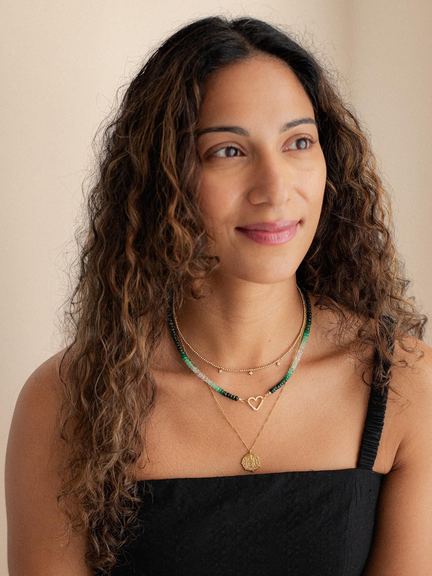 Emerald heart-shaped 14K gold carabiner necklace by Earthly Abundance, featuring a delicate chain and vibrant gemstone pendant.