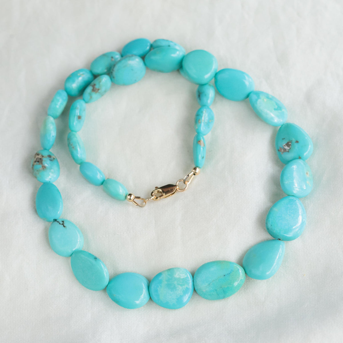 Turquoise sol necklace in 14K gold from Earthly Abundance featuring a vibrant turquoise pendant on a delicate gold chain.