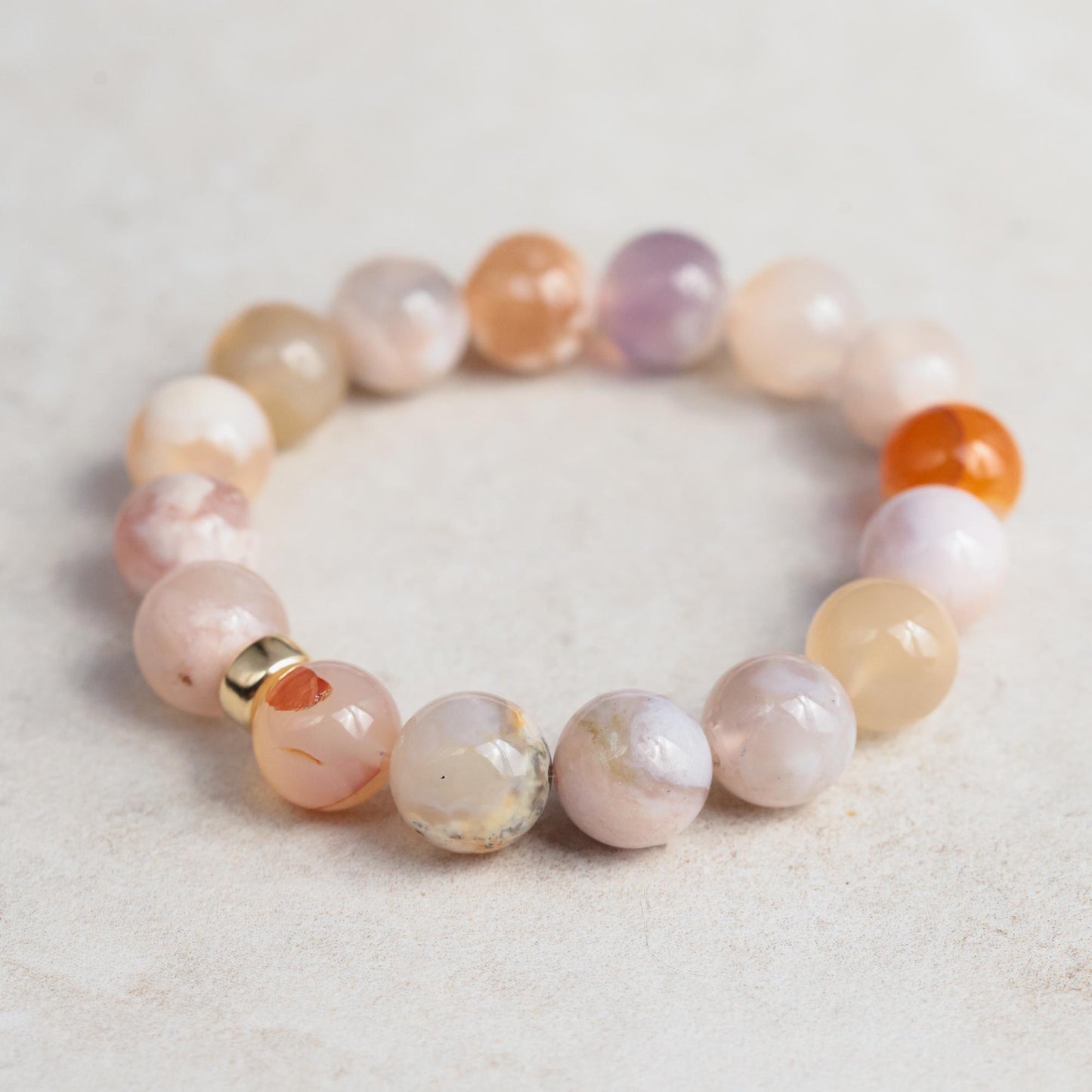 Flower agate bracelet featuring polished stones and a 14K gold clasp, showcasing vibrant floral patterns and natural gemstone beauty.