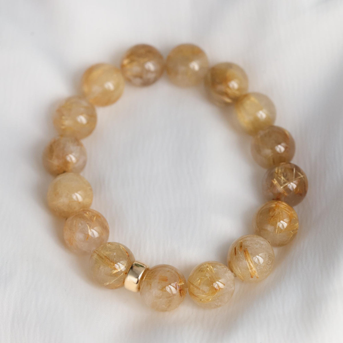Golden rutilated quartz bracelet with 14K gold accents from Earthly Abundance, featuring polished gemstone beads and intricate gold details.