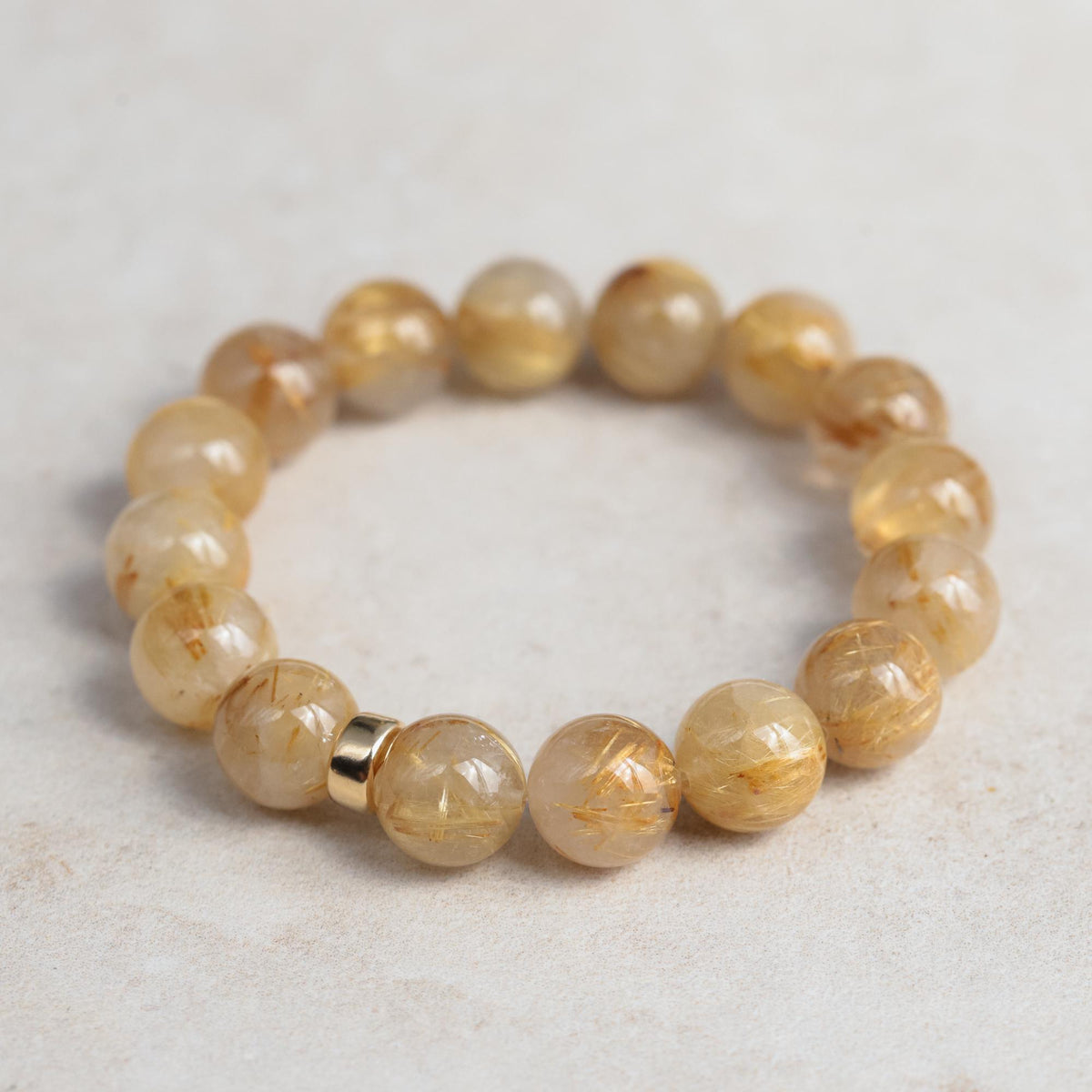 Golden rutilated quartz bracelet with 14K gold accents from Earthly Abundance, featuring polished stone beads and intricate gold details.