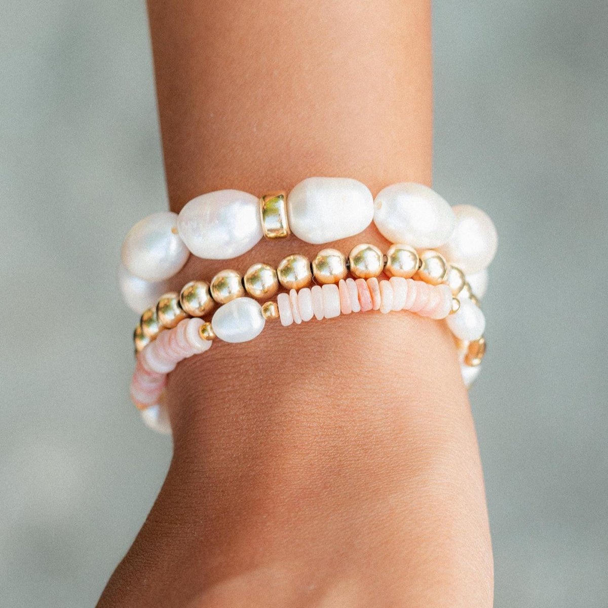 Stack of pearl and gold harmony rings from Earthly Abundance, featuring layered pearl and gold jewelry on a neutral background.