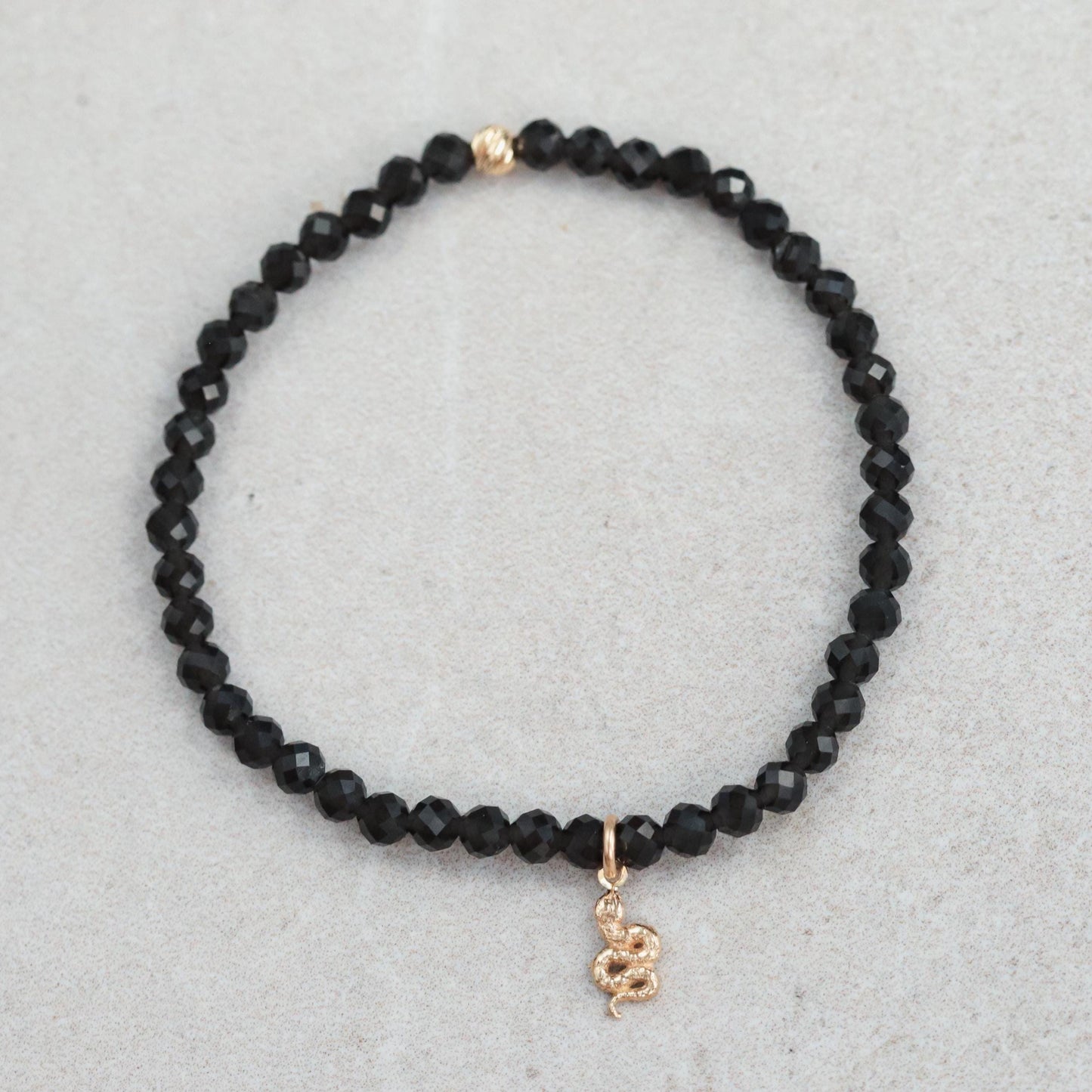 Obsidian snake bracelet crafted with 14K gold from Earthly Abundance, featuring a detailed snake design on a sleek black obsidian band.