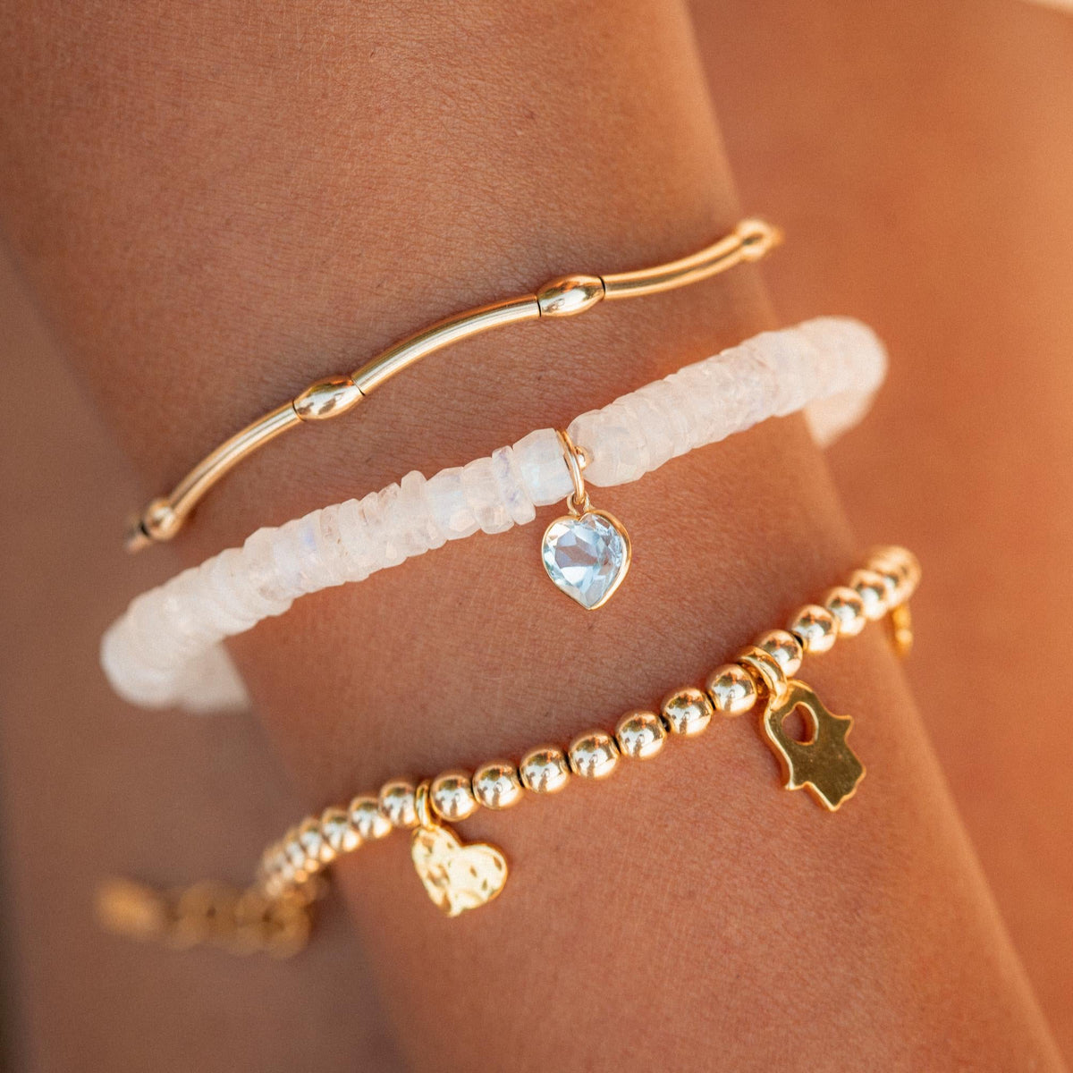 Moonstone bracelet with blue topaz heart charm, 14K gold from Earthly Abundance, featuring polished gemstones and elegant design.