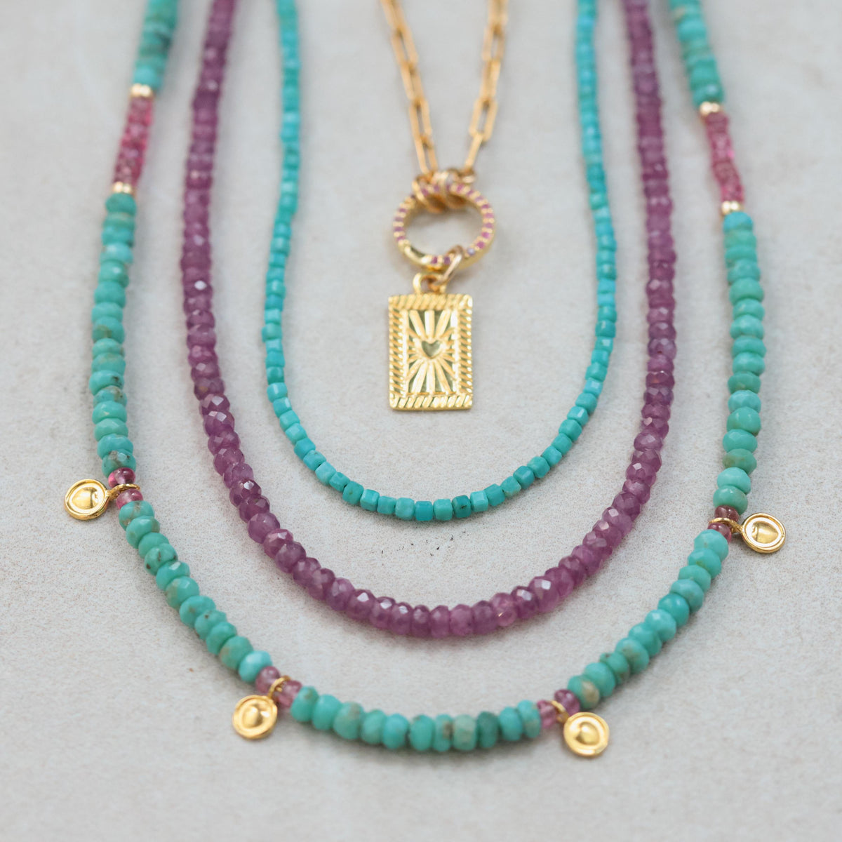 African Ruby necklace featuring vibrant red gemstones on a delicate gold chain, styled with elegant jewelry.
