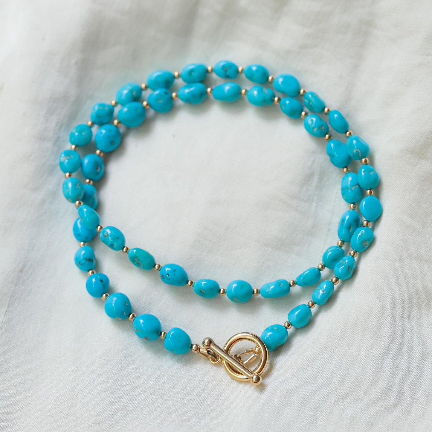 Sleeping Beauty toggle necklace by Earthly Abundance featuring a vibrant turquoise gemstone pendant on a silver chain.