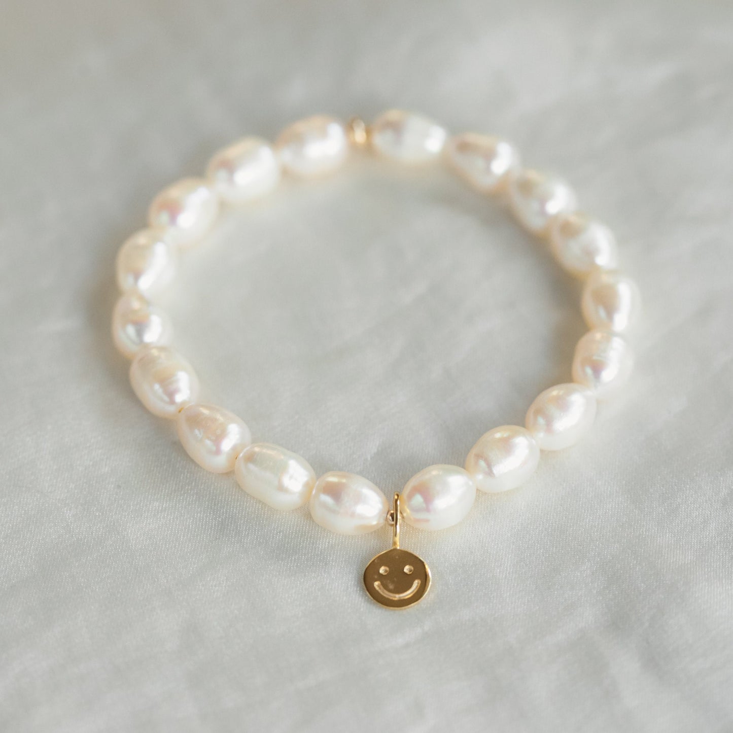 Happy Face Freshwater Pearl bracelet by Earthly Abundance featuring a string of lustrous freshwater pearls with a cheerful face charm.