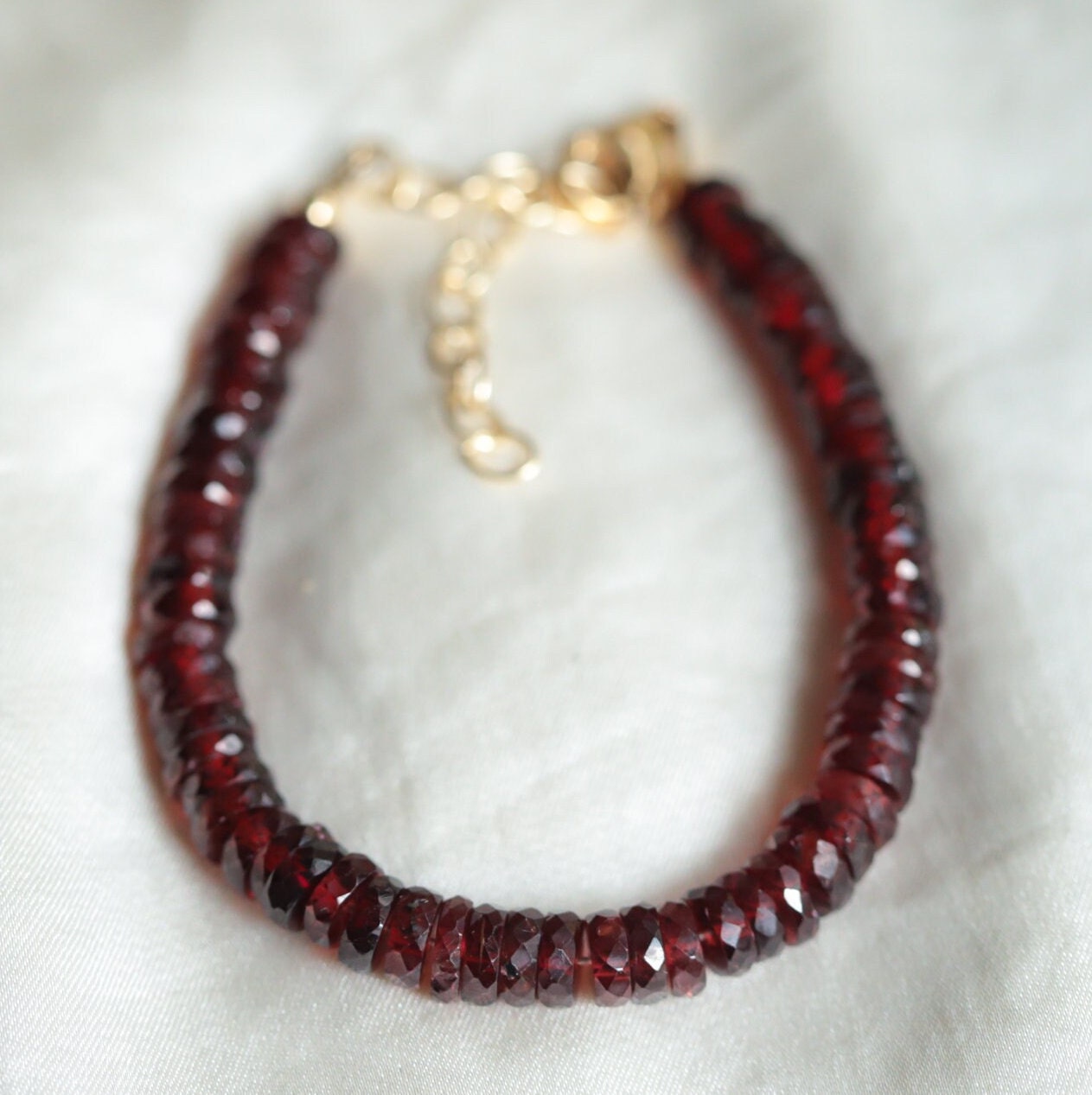 Faceted Heishi Garnet bracelet with small round red garnet beads on a stretch cord, styled for elegant jewelry wear.