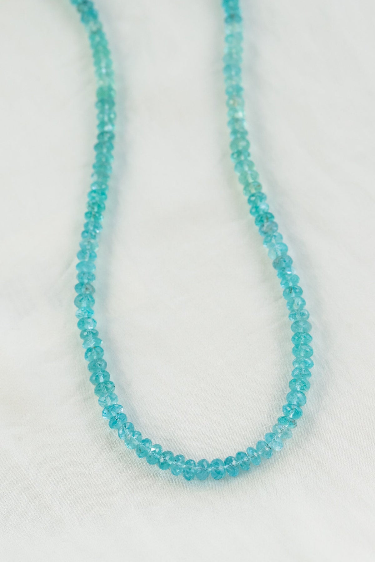 A blue apatite heart-shaped pendant on a silver carabiner necklace, displayed against a neutral background.