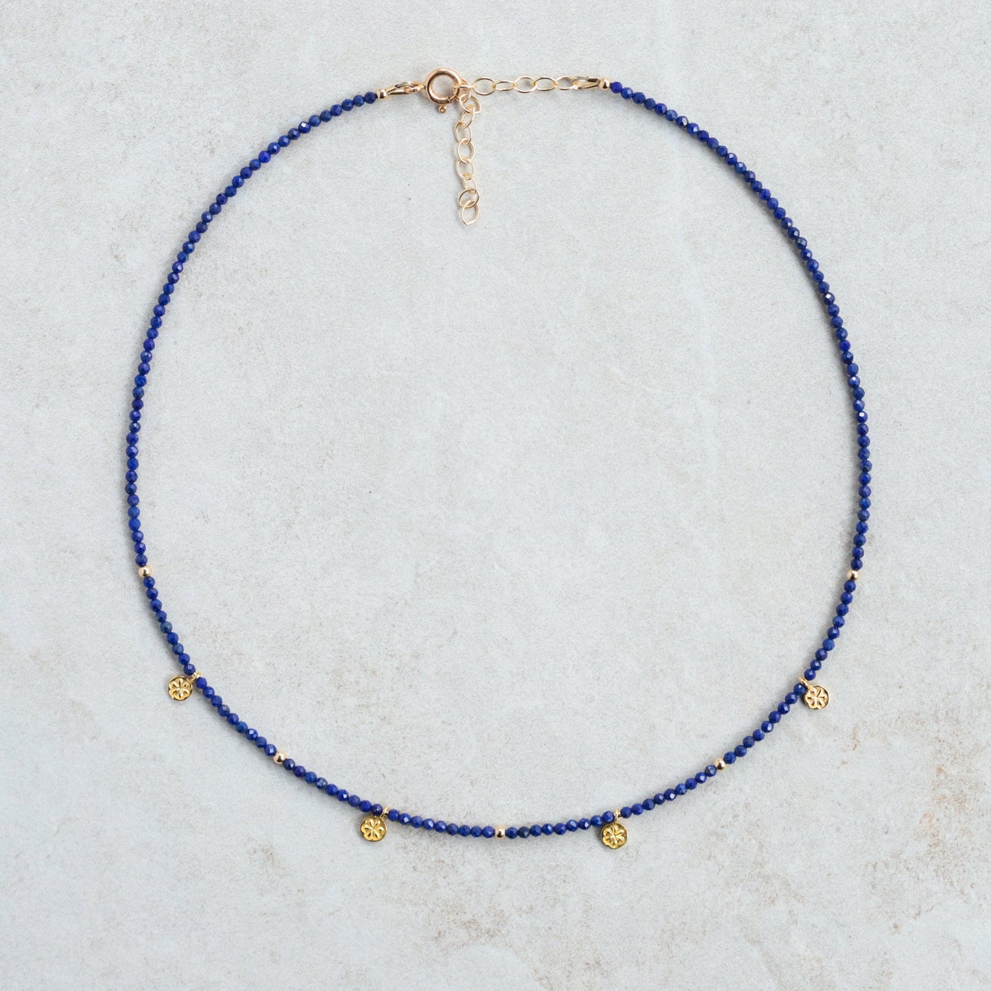 Lapis Daisy Necklace by Earthly Abundance featuring a delicate gold chain with a blue lapis lazuli flower pendant.