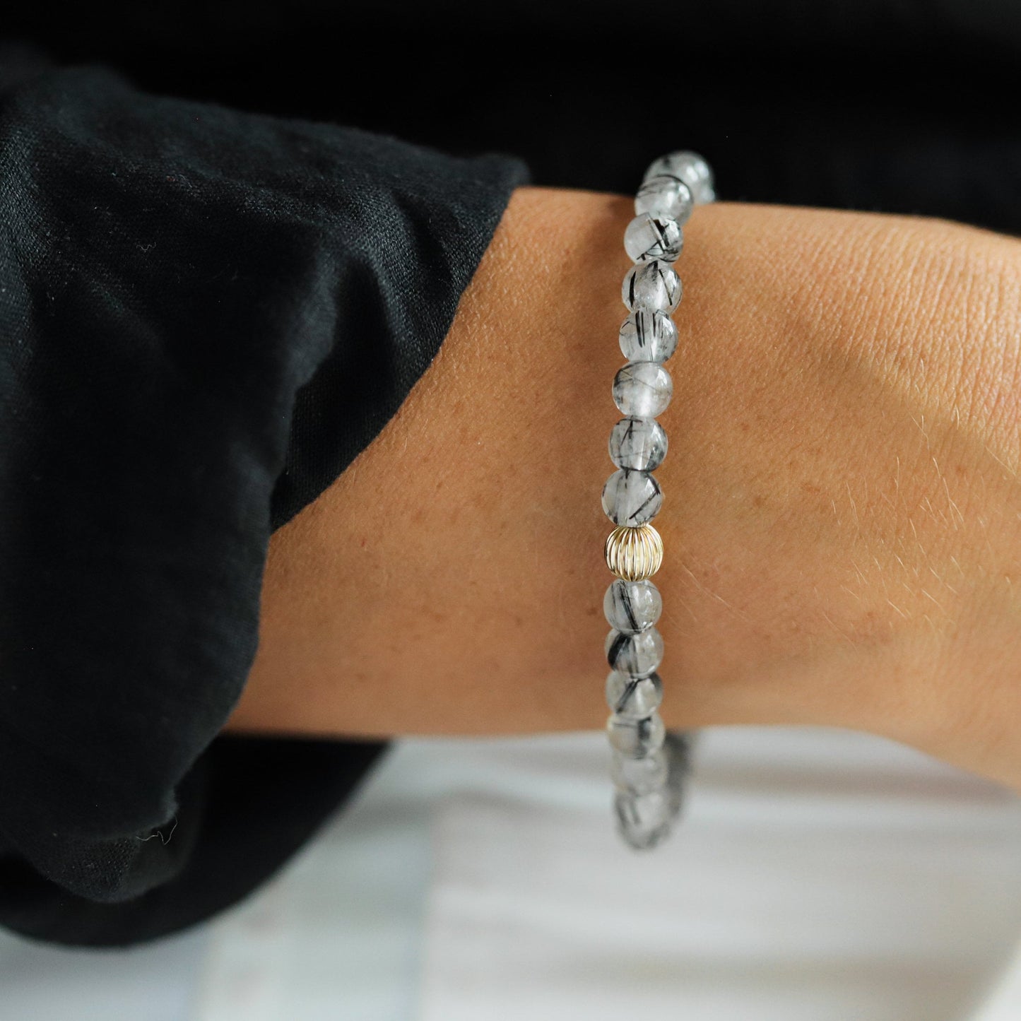 Black rutilated quartz gemstone from Earthly Abundance Jewelry, showing its dark crystal with golden rutile inclusions.