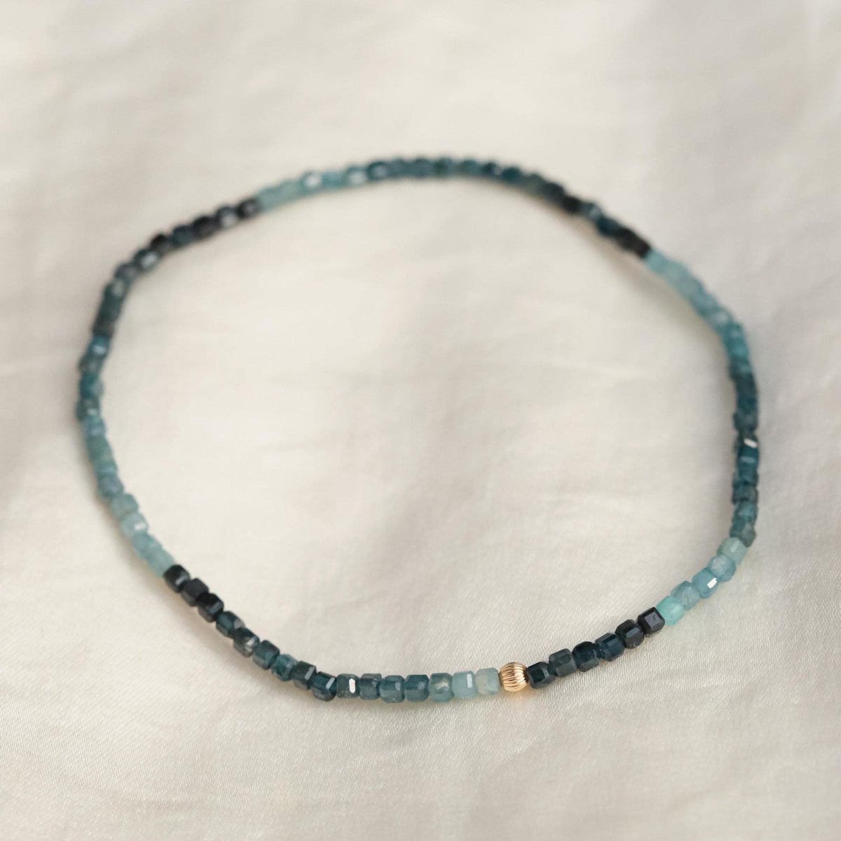 Earthly Abundance Grandidierite cube bracelet featuring blue-green gemstone beads on a stretch cord.