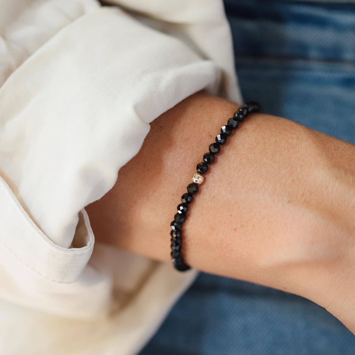 Black Tourmaline bracelet with 4mm beads on a stretch cord, featuring a 14K gold accent, from Earthly Abundance Jewelry.