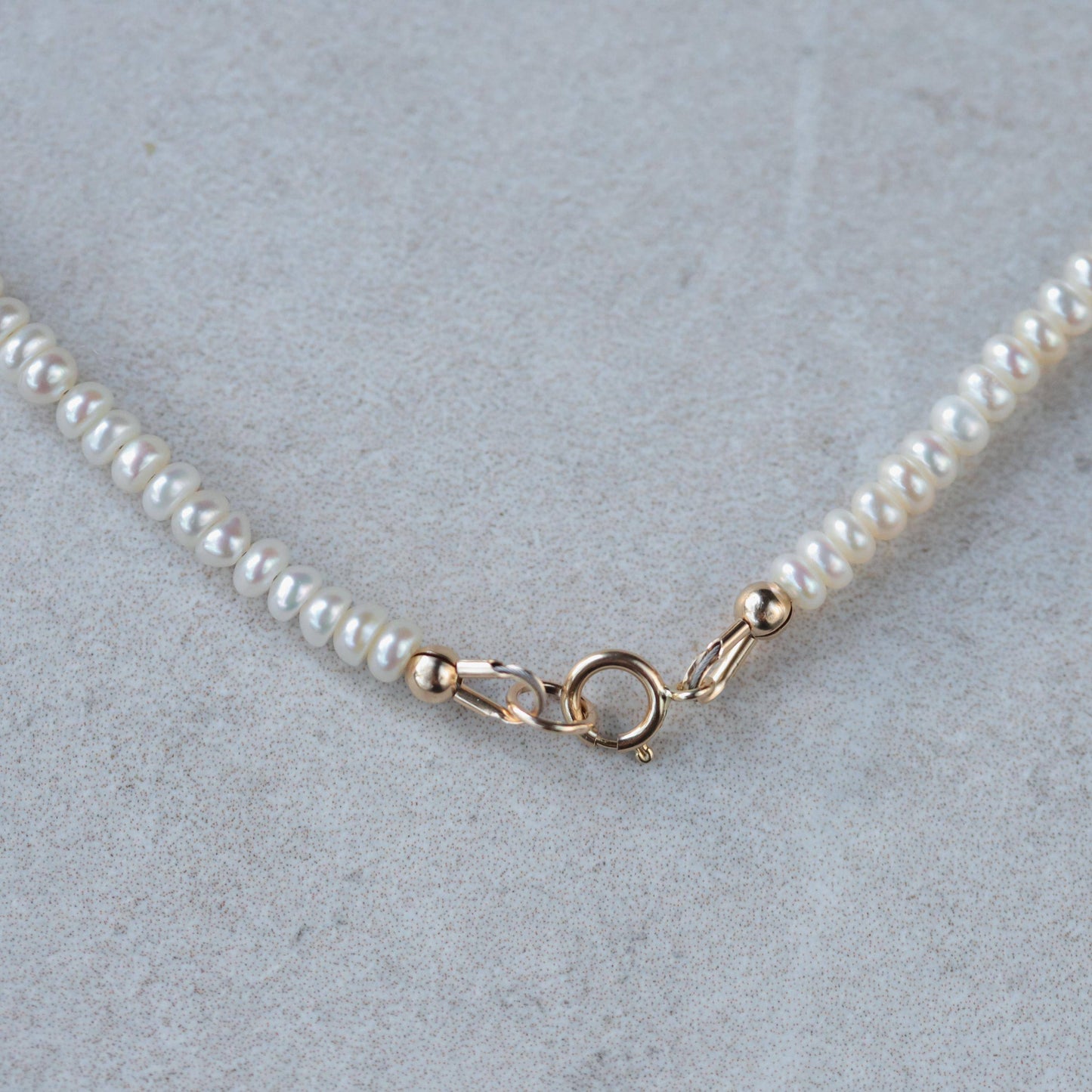 Freshwater pearl necklace with 14K gold clasp from Earthly Abundance Jewelry, featuring lustrous white pearls on a delicate chain.