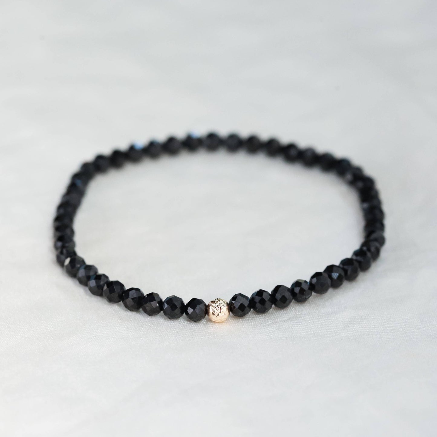 Black Tourmaline bracelet with 4mm beads from Earthly Abundance Jewelry, featuring a 14K clasp, displayed on a neutral background.