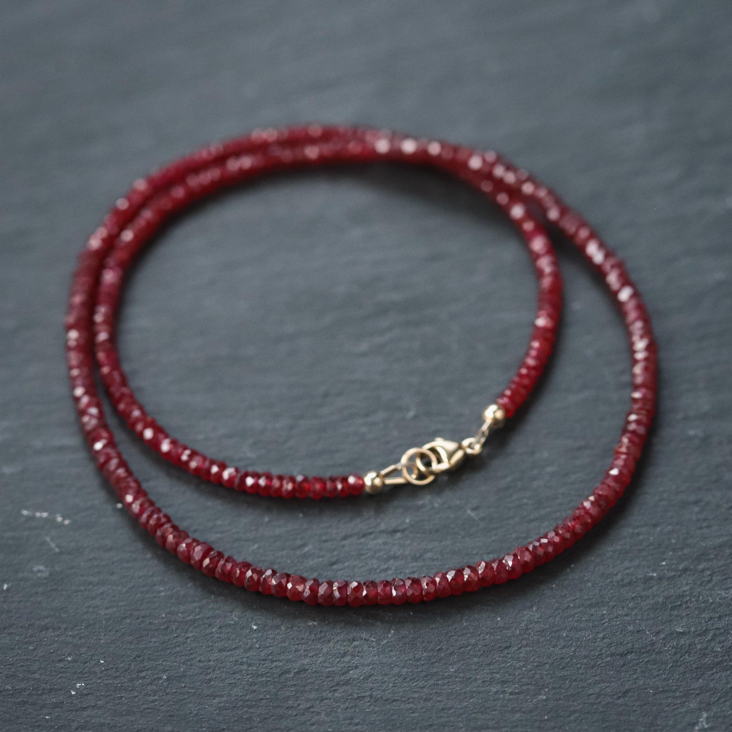 Verona Longido Ruby Necklace by Earthly Abundance featuring a 14K gold chain and vibrant red ruby pendant.