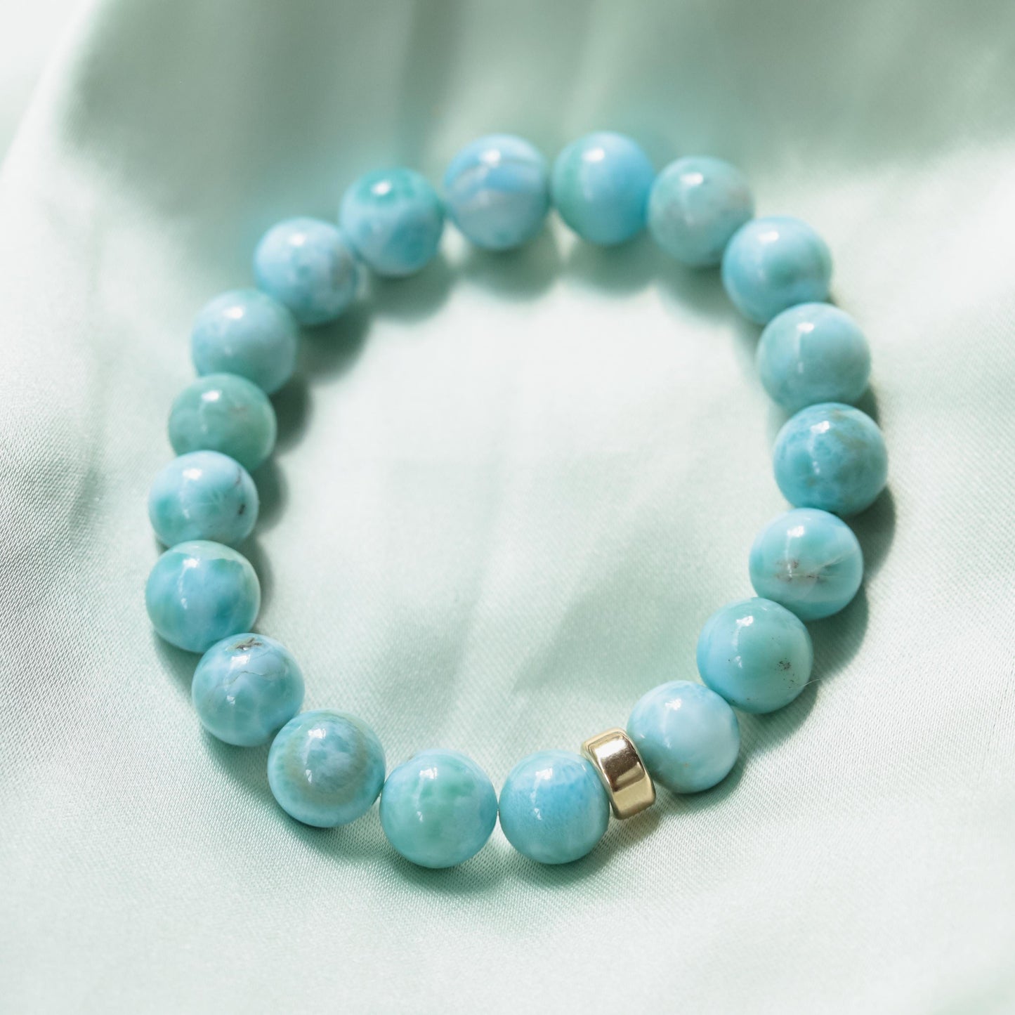 Larimar bracelet with 10mm beads featuring 14K gold accents, crafted by Earthly Abundance, displayed on a neutral background.