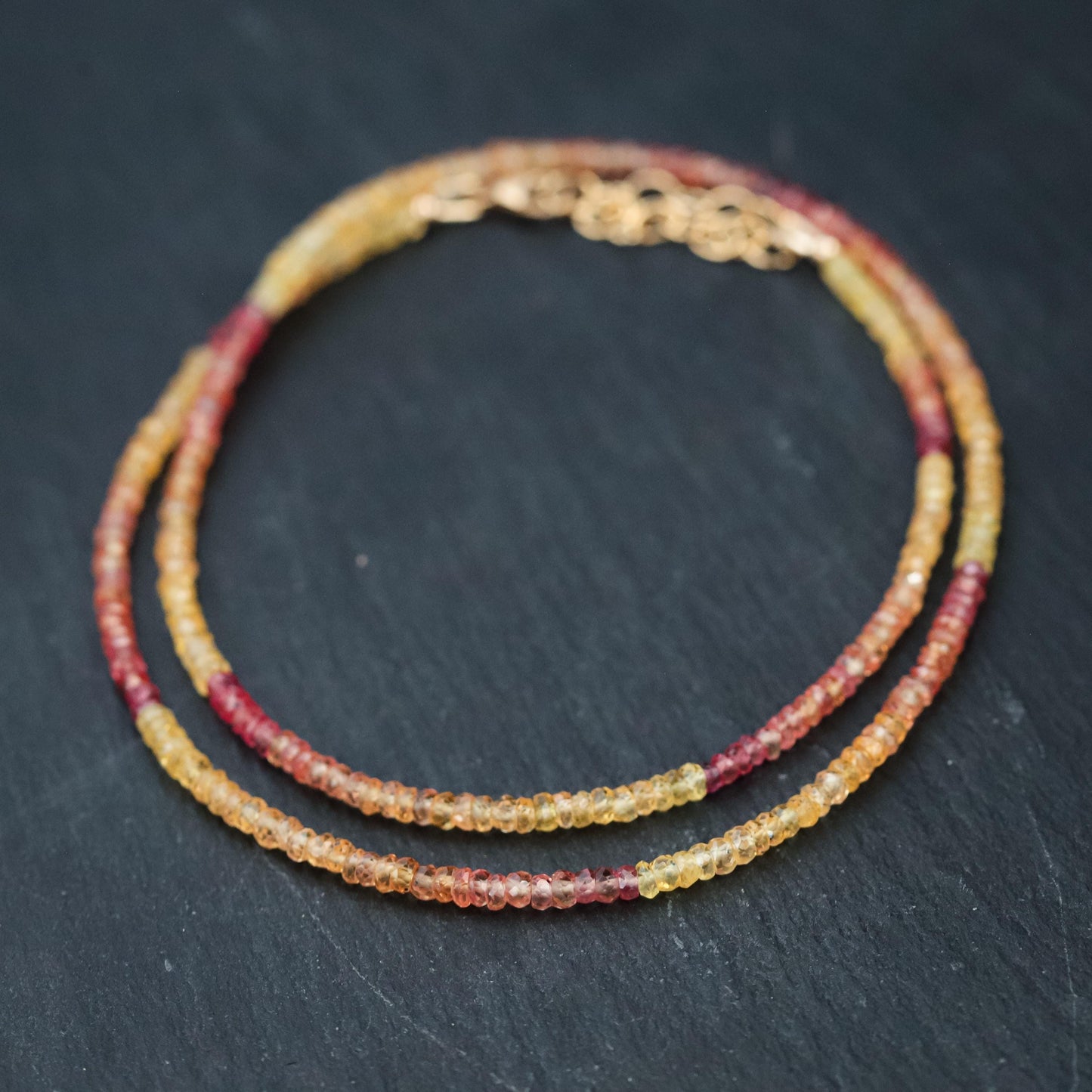 Pink and yellow Songea sapphire necklace featuring a delicate gold chain and vibrant gemstone pendants, showcasing elegant jewelry design.