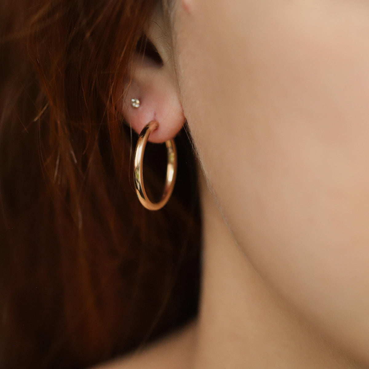 14K gold-filled effortless hoop earrings by Earthly Abundance, showcasing smooth, shiny gold hoops on a plain background.