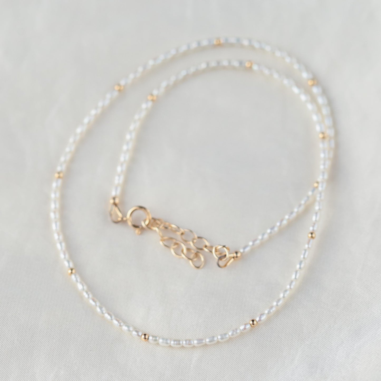 Freshwater pearl necklace with 14K gold clasp from Earthly Abundance, featuring lustrous white pearls on a delicate chain.
