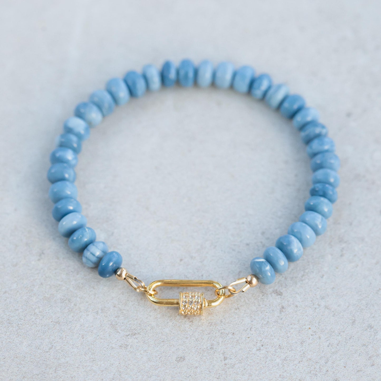 Blue opal topaz bracelet featuring polished gemstone beads on a stretch cord, showcasing vibrant blue and teal hues.