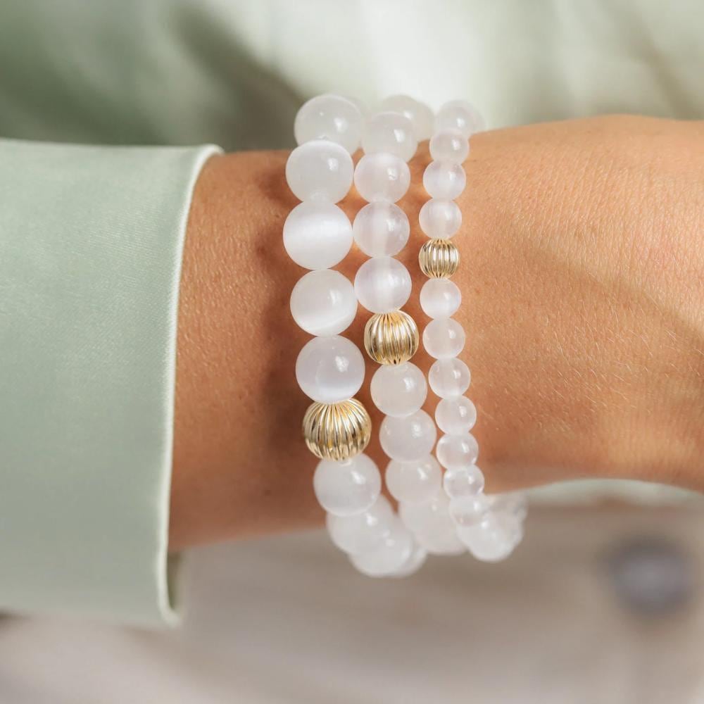 Earthly Abundance Jewelry Selenite bracelet with smooth, translucent white stones on an elastic band, close-up view of the jewelry.