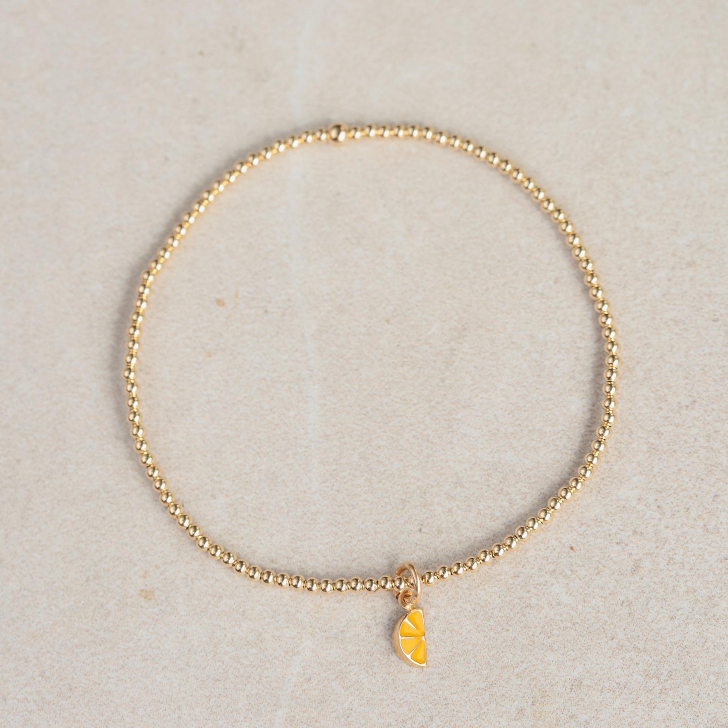 14K lemon charm bracelet from Earthly Abundance featuring a detailed lemon pendant on a delicate chain.