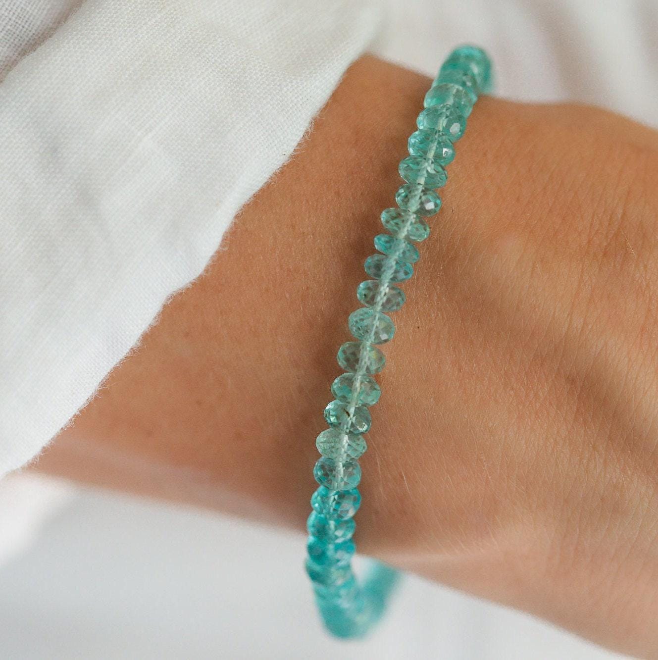 Apatite bracelet featuring 14K gold clasp and beads, showcasing blue-green apatite stones on a white background.