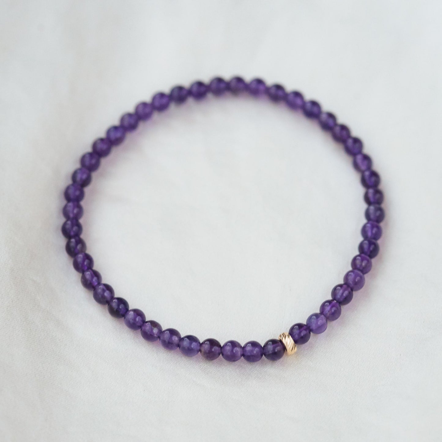Amethyst bracelet with 14K gold accents from Earthly Abundance Jewelry, showcasing polished purple stones on a delicate chain.