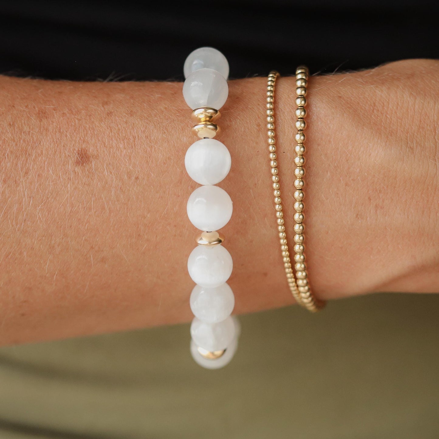 Earthly Abundance Selenite 10mm bracelet featuring smooth white selenite beads on an elastic band, close-up view.