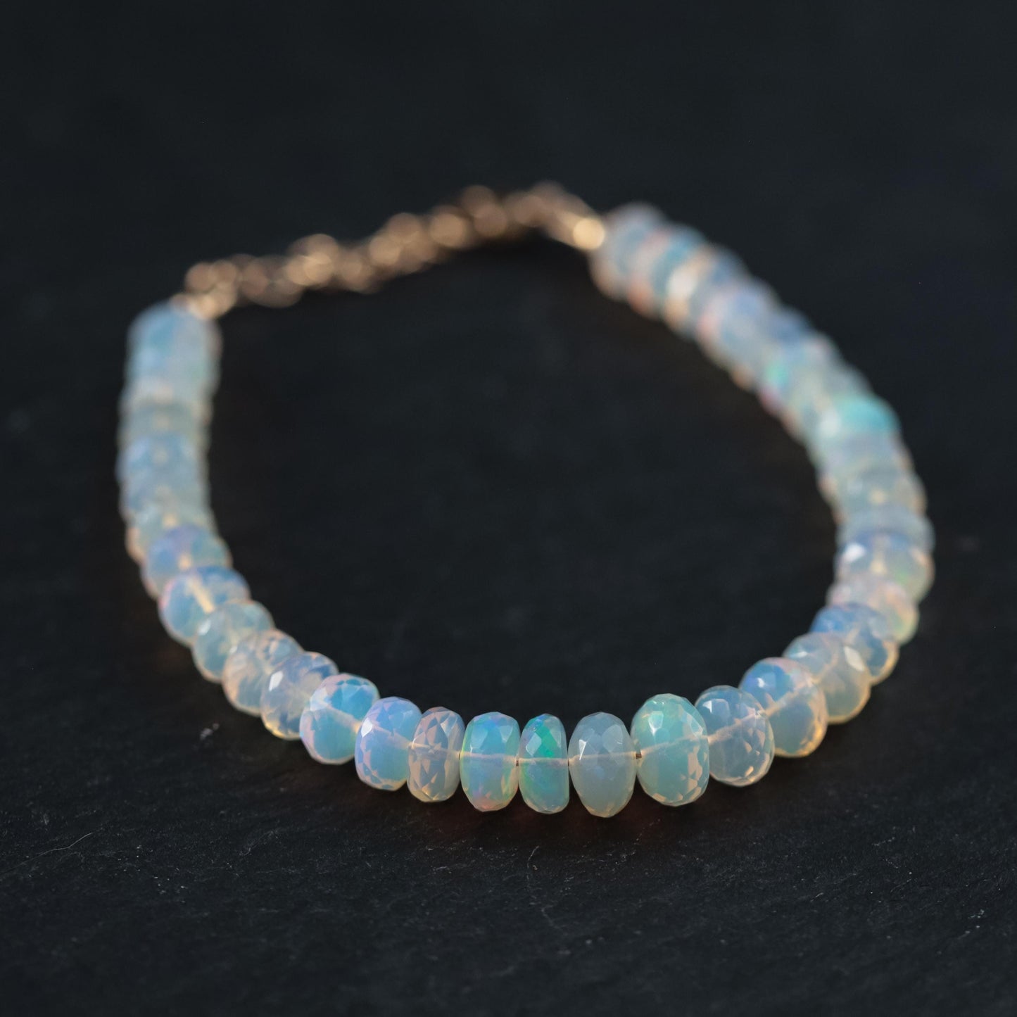 Soft fire opal bracelet with 14K gold setting from Earthly Abundance, showcasing smooth, glowing fire opal gemstones on a delicate chain.