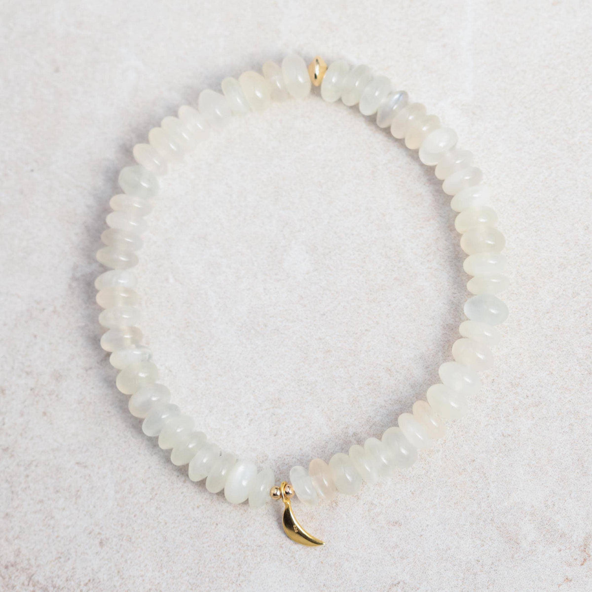 White creamy moonstone bracelet featuring polished round moonstone beads on an elastic band, displayed against a neutral background.