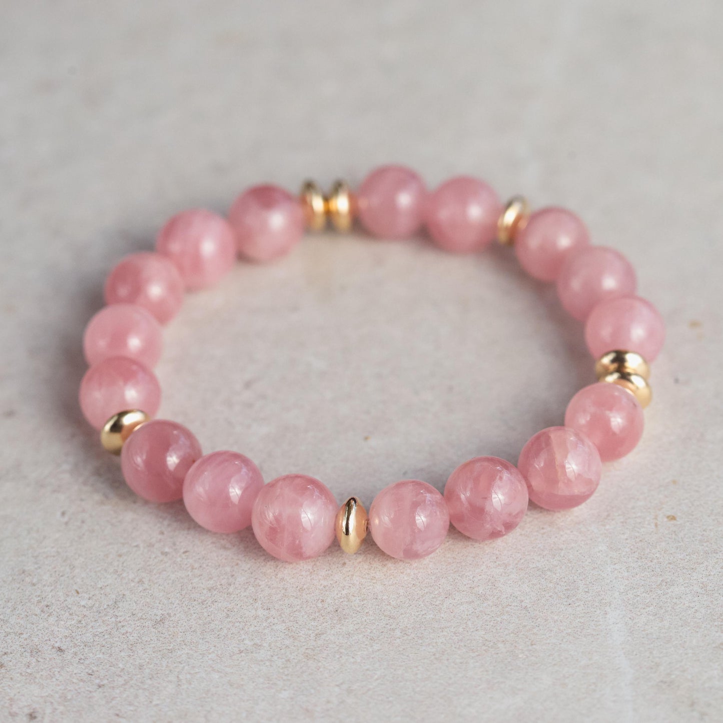 Madagascar Rose Quartz bracelet featuring 10mm pink gemstone beads by Earthly Abundance, displayed on a neutral background.