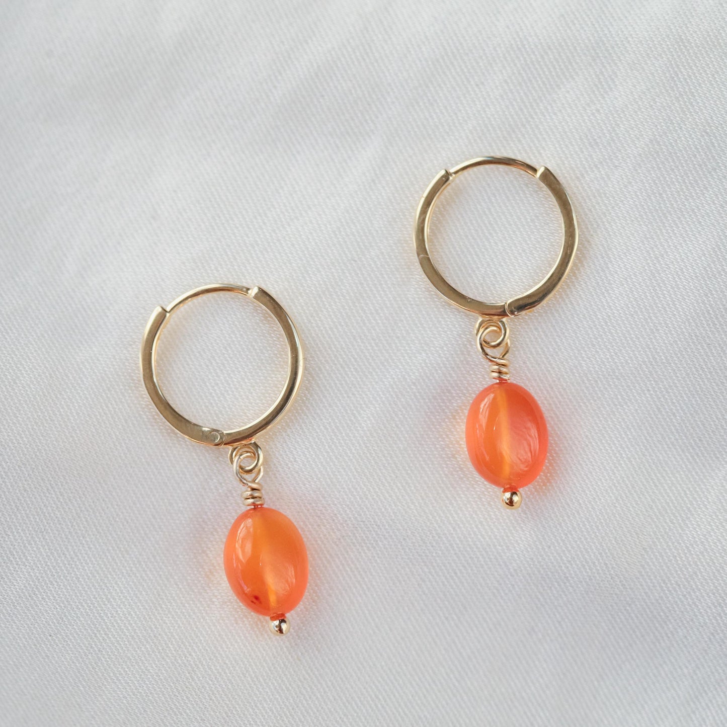 Earthly Abundance Carnelian glow hoops jewelry with vibrant orange-red orange beads and gold hoop design.