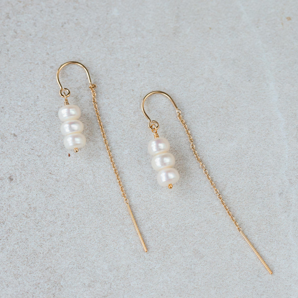Freshwater pearl threader earrings by Earthly Abundance featuring elegant pearl strands and sleek gold-toned hooks.