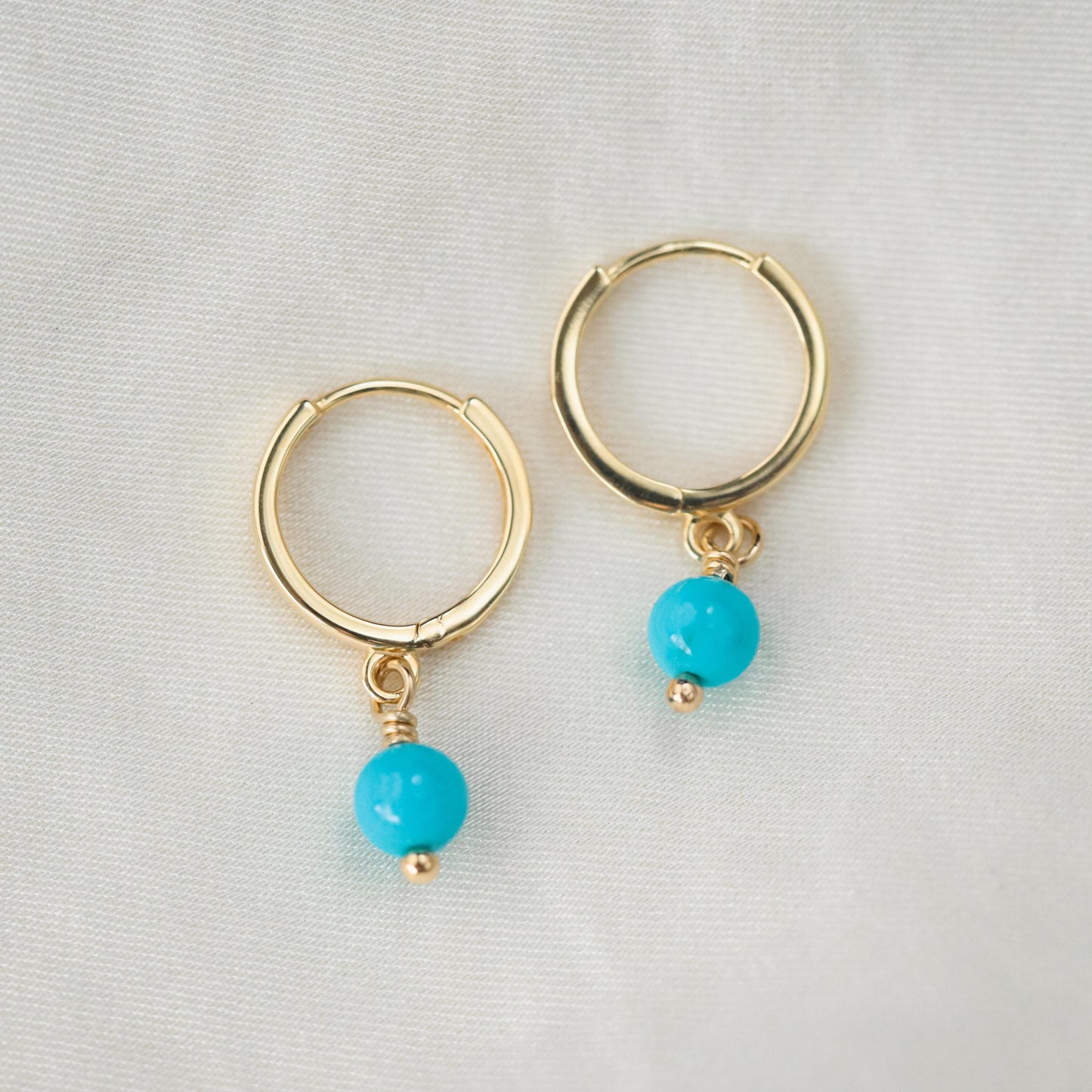 Turquoise hoop earrings from Earthly Abundance featuring 14K gold, showcasing vibrant turquoise stones in a classic hoop design.
