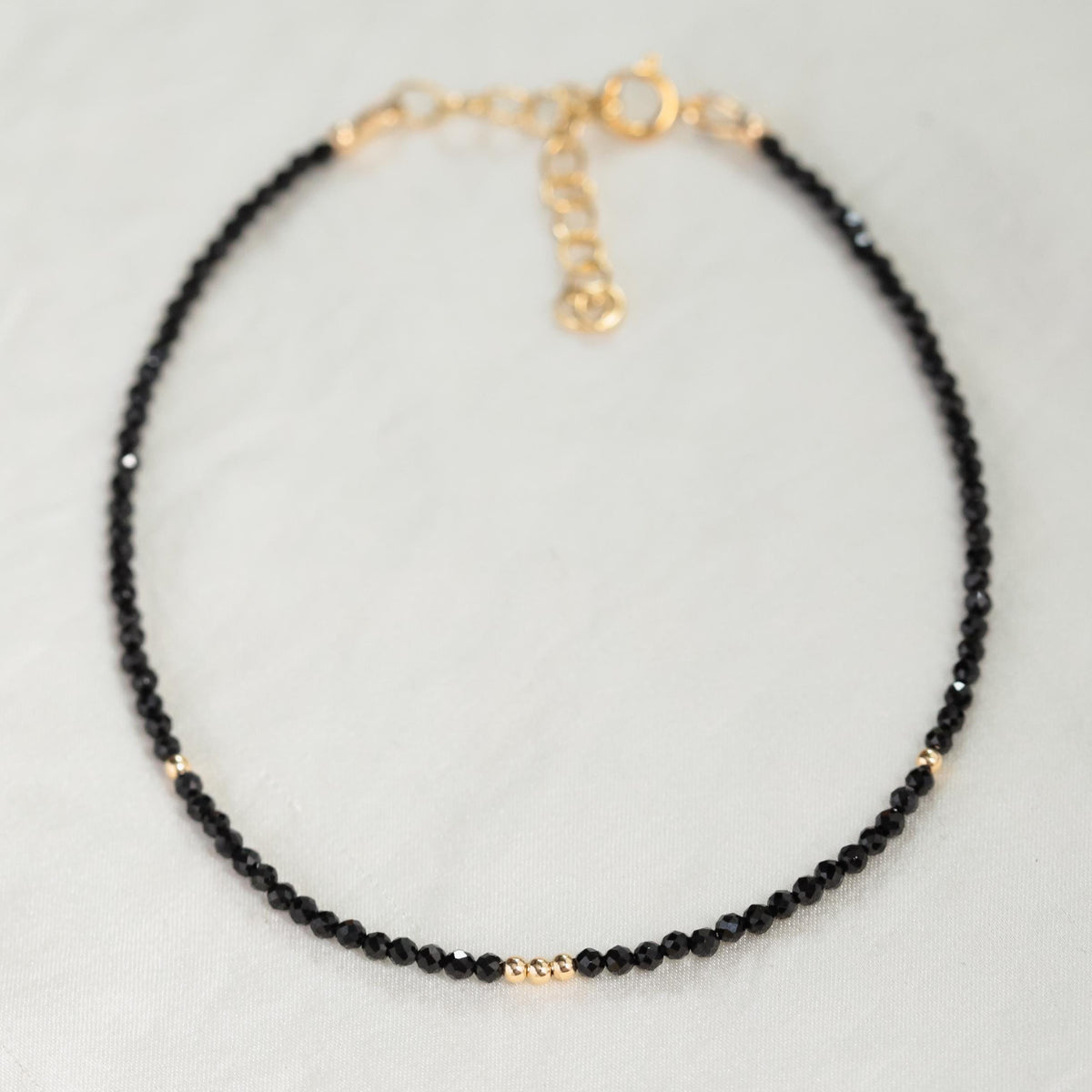 Black spinel anklet from Earthly Abundance featuring a delicate chain with polished black spinel beads for elegant ankle jewelry.