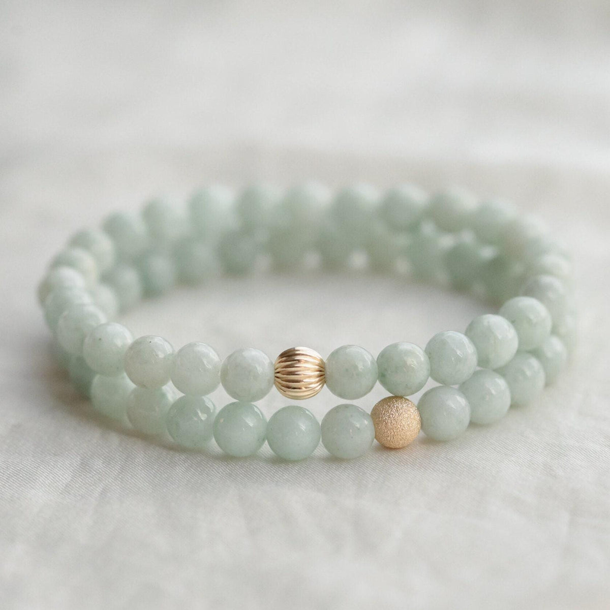 Sixmm jadeite bead from Earthly Abundance Jewelry, showcasing smooth, polished green jadeite gemstone on a jewelry strand.