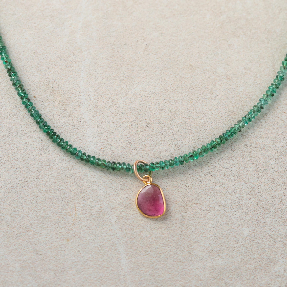 Zambian emerald and pink tourmaline pendant necklace with silver chain from Earthly Abundance, close-up of vibrant gemstones.