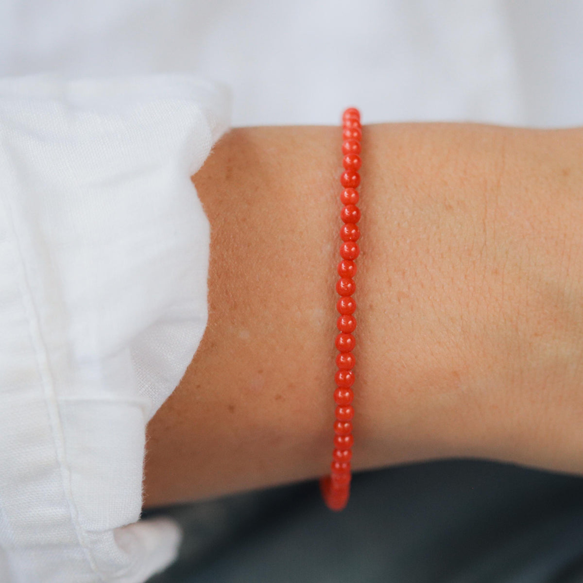Italian Coral 3mm beads from Earthly Abundance Jewelry, showcasing vibrant red-orange coral strands on a jewelry display.