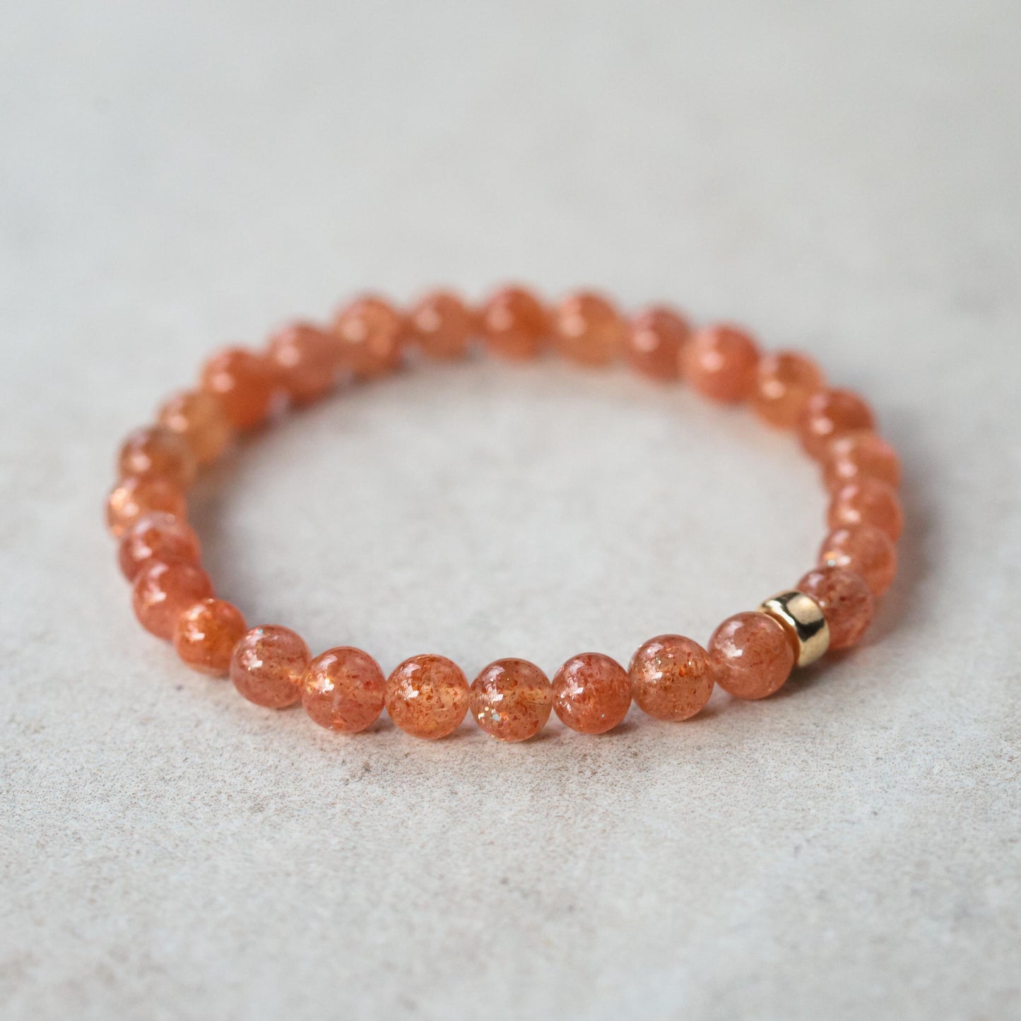 Earthly Abundance Sunstone bracelet with 6mm round beads, showcasing warm orange and shimmering natural stone on a neutral background.