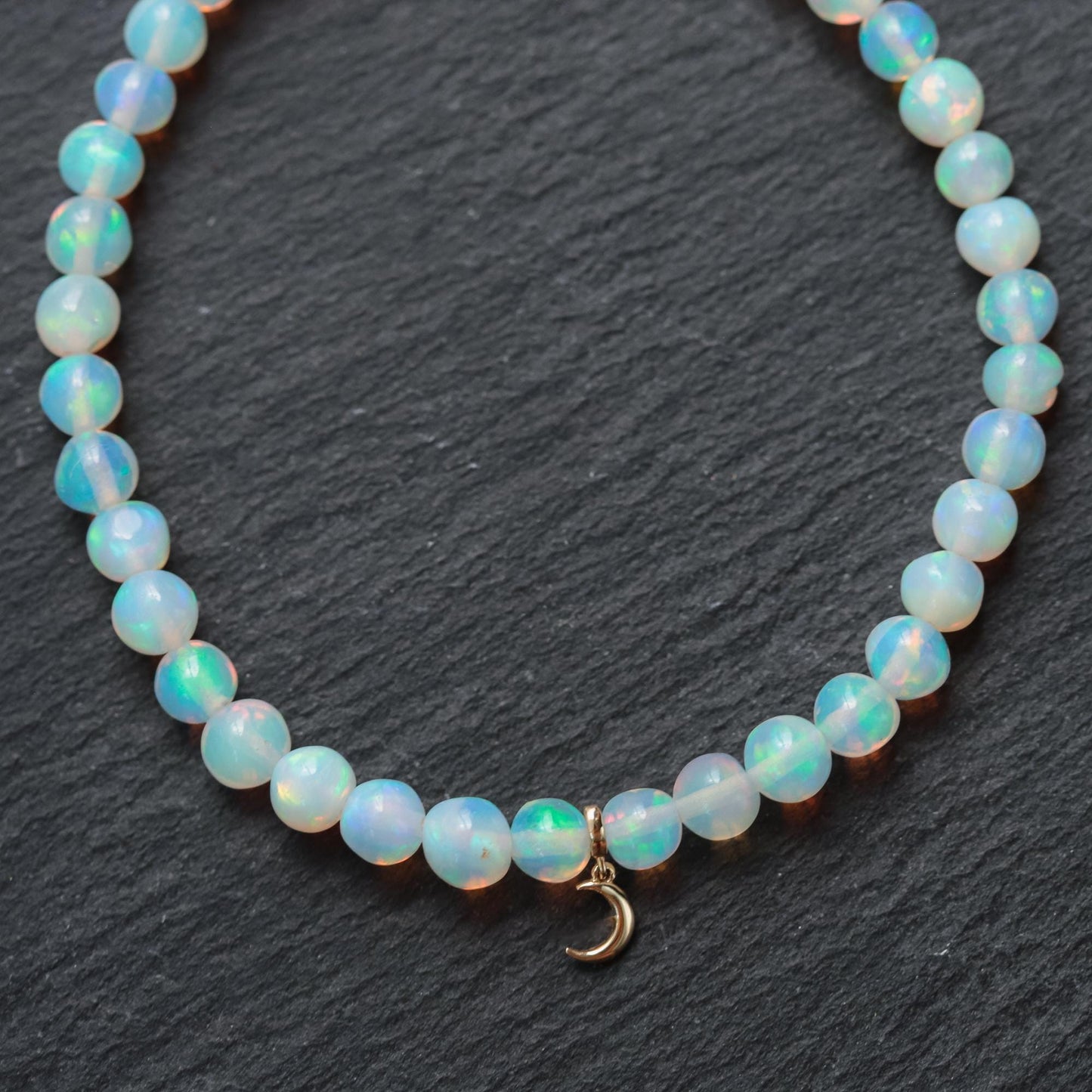 Ethiopian Opal Moon bracelet with 14K gold setting from Earthly Abundance, featuring moon-shaped opal stones.