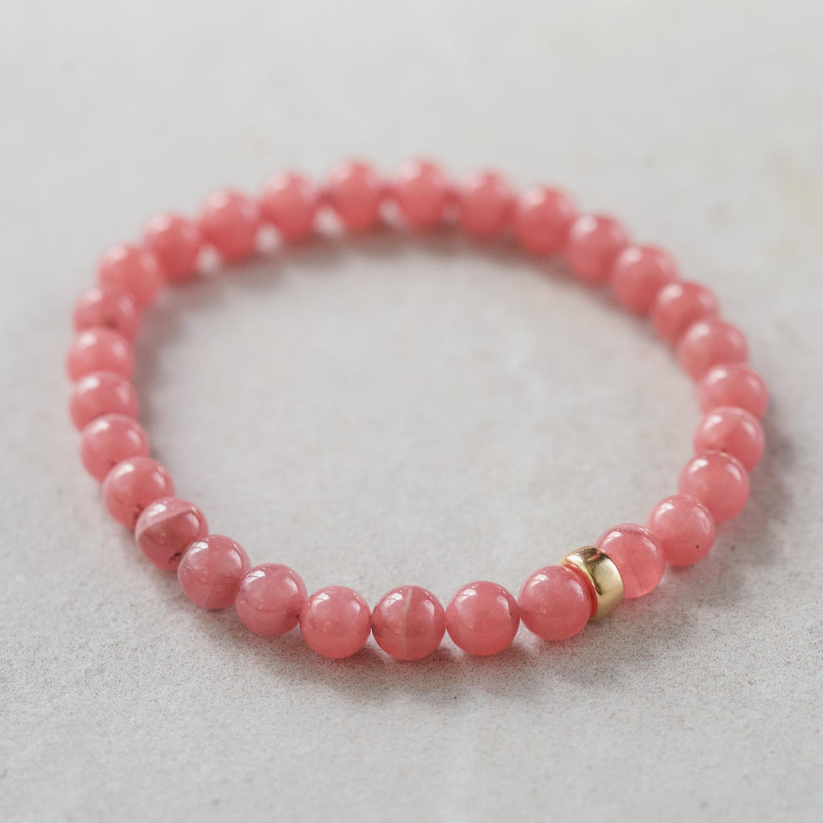 Rhodochrosite gemstone pendant in 14K gold from Earthly Abundance Jewelry, featuring a polished pink stone with gold setting.